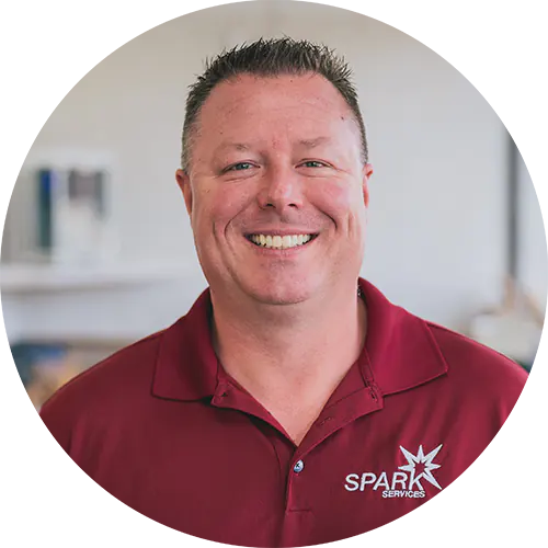 Smiling man in maroon polo with SPARK SERVICES logo, representing VoIP solutions for managed service providers.