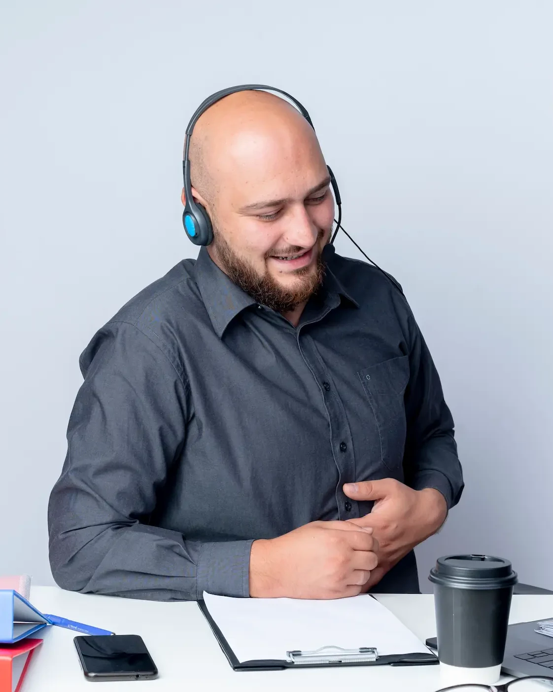 A smiling support agent wearing a headset at his desk, taking a call.